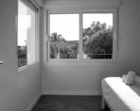 Una fotografía en blanco y negro de un dormitorio con una cama y una ventana.