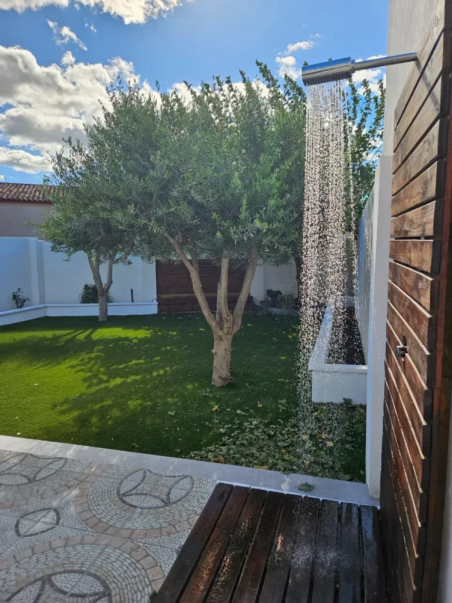Una ducha en un patio trasero con un árbol al fondo.