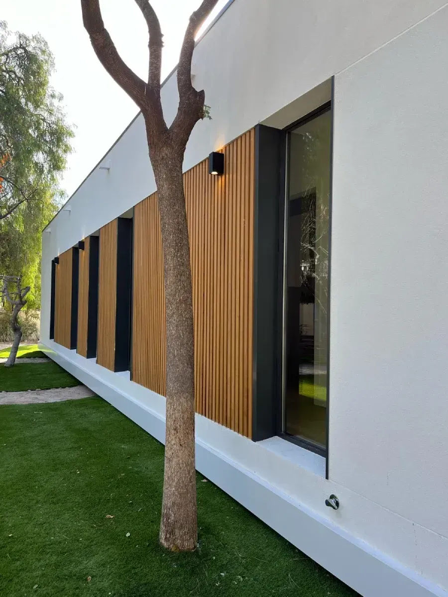 Un edificio blanco con un árbol delante.