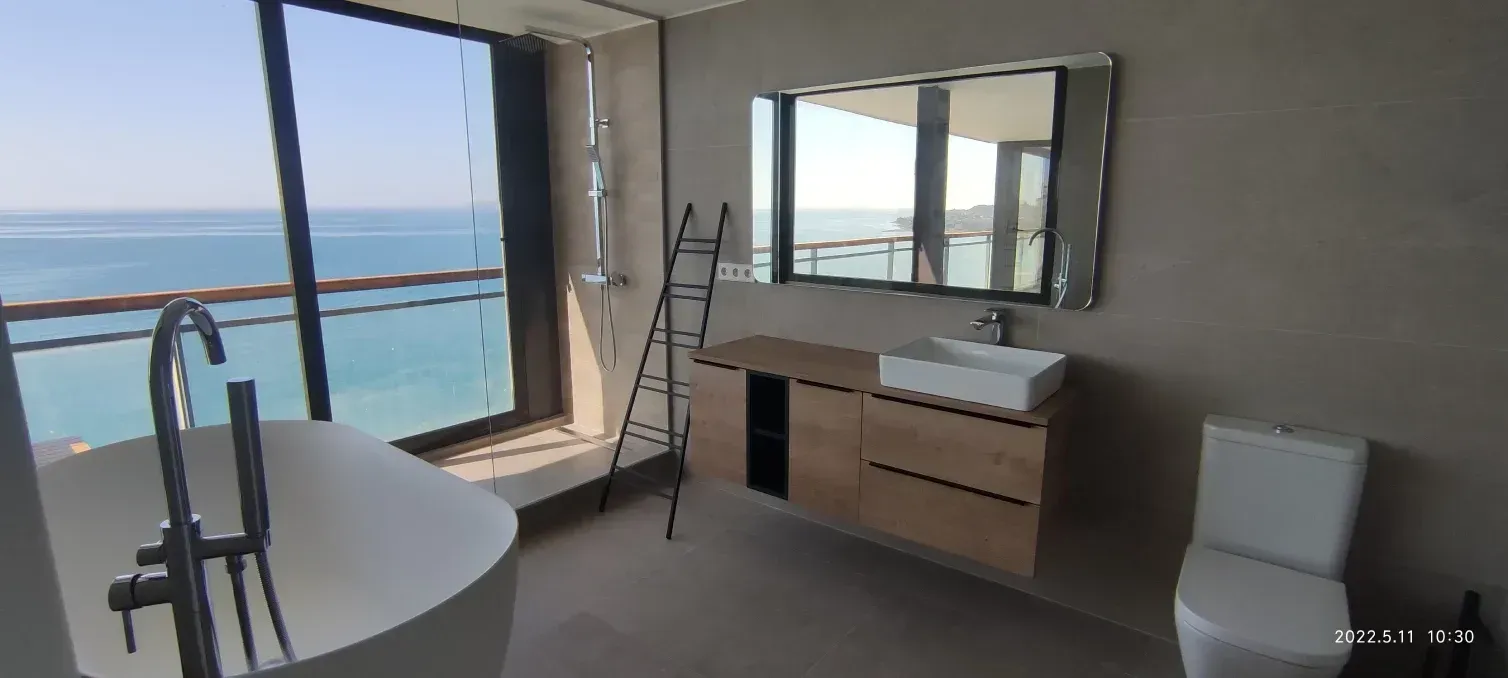 Un baño con una gran ventana con vista al mar.