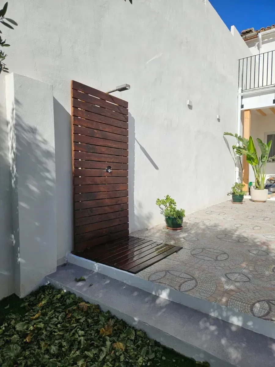 Una pared blanca con una ducha de madera delante.