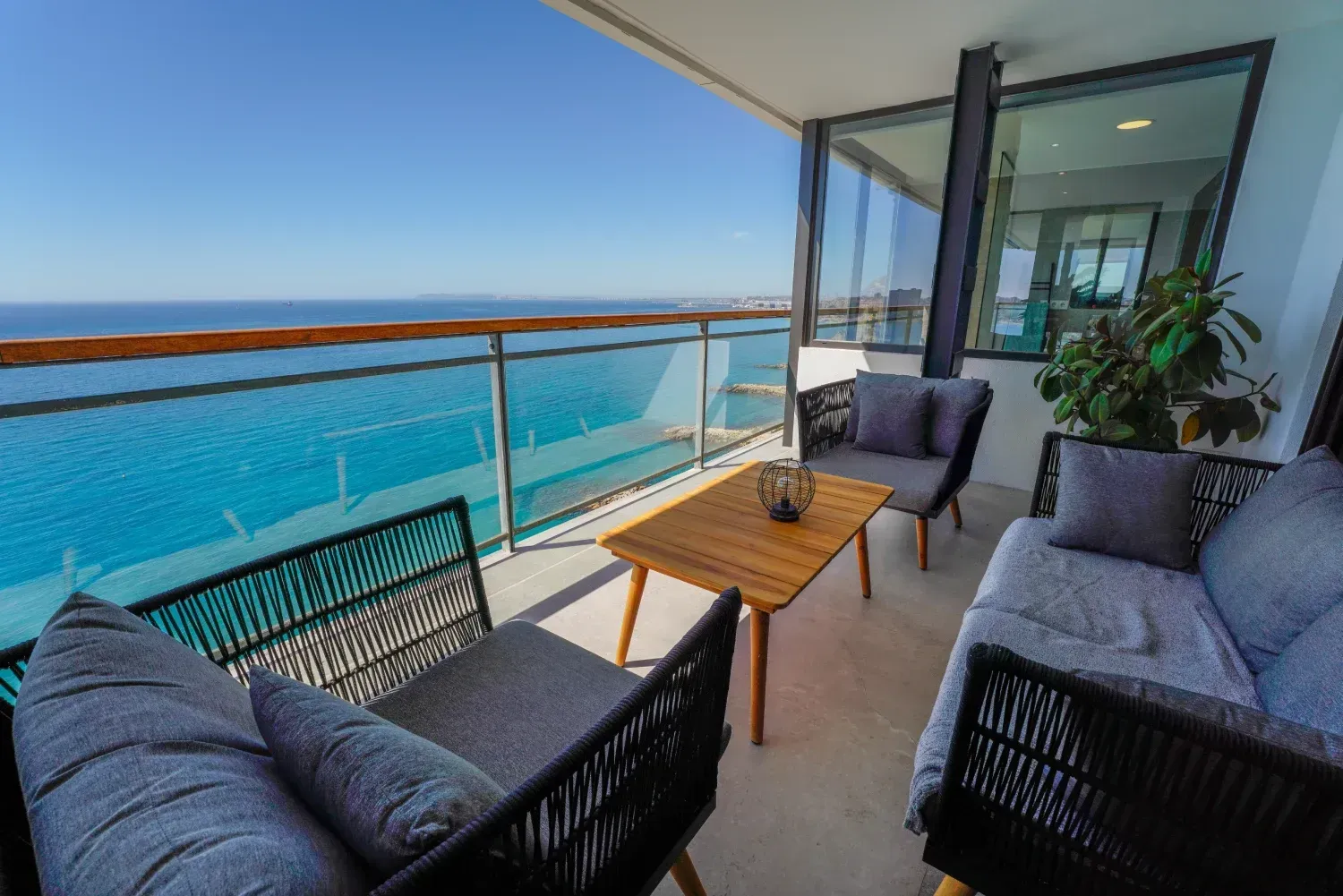 Un balcón con sofá y sillas con vista al mar.