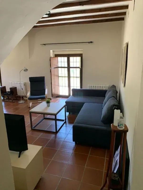 Luminoso salón con sofá modular gris, mesa de centro, televisor, suelo de baldosas de terracota