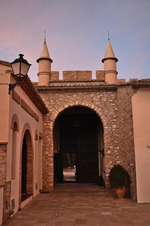 Portal de piedra con torres gemelas al atardecer, visto desde un estrecho pasillo del patio.