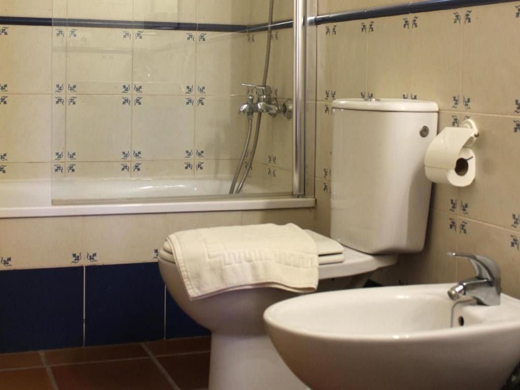 Baño pequeño con inodoro, lavabo, bañera y cortina de ducha.