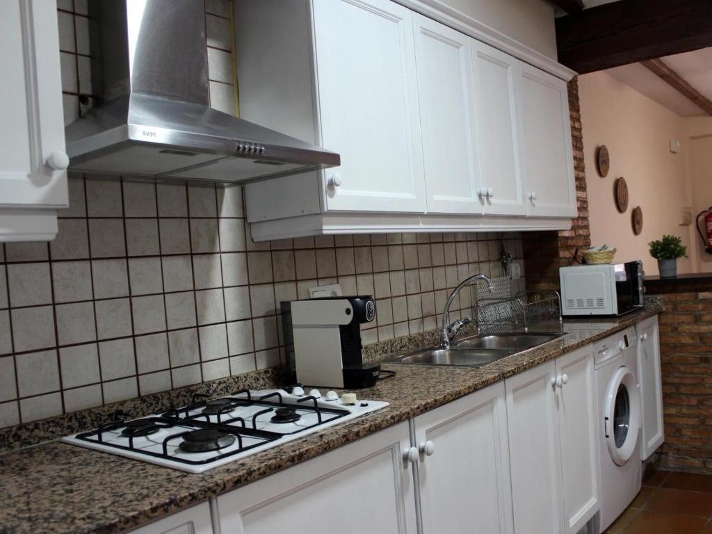 Cocina moderna con gabinetes blancos, salpicadero de azulejos, encimera de granito, placa de cocina