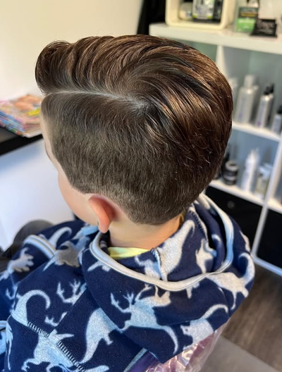 Person, die sich mit einer elektrischen Haarschneidemaschine die Haare schneiden lässt; Friseursalon-Ambiente.