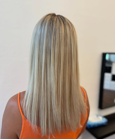 Friseurin benutzt in einem Salon einen Haartrockner und eine Bürste für das Haar einer Kundin.