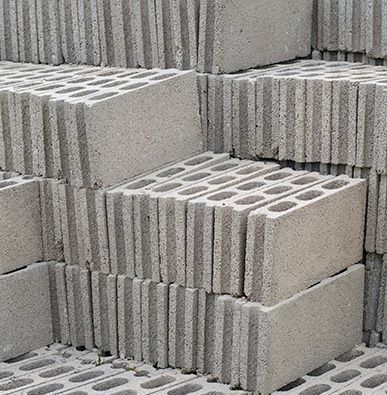 Una pila de bloques de hormigón gris, cada uno con dos filas de cavidades rectangulares huecas.