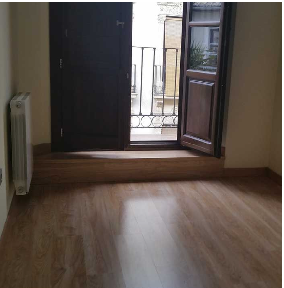 Una habitación vacía con un balcón y una puerta abierta.