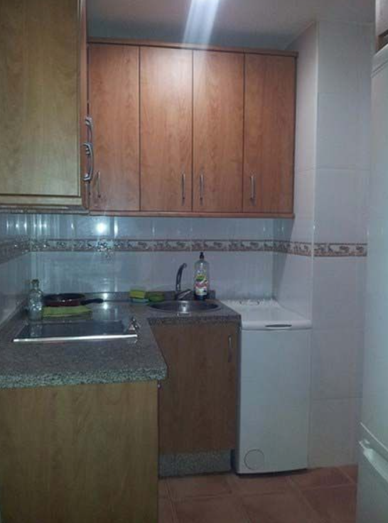 Una cocina con muebles de madera y lavadora.