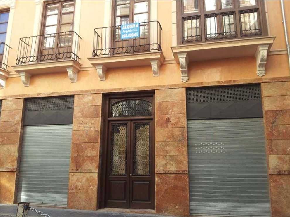 Un edificio con un cartel en el balcón que dice 'alquiler'