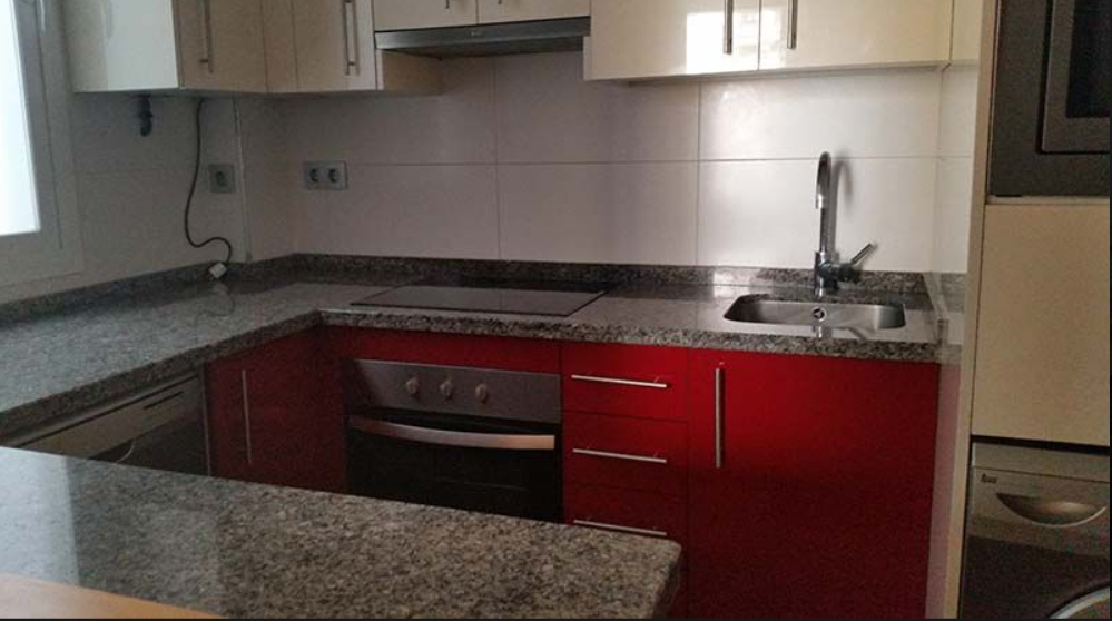 Una cocina con gabinetes rojos y encimeras de granito.