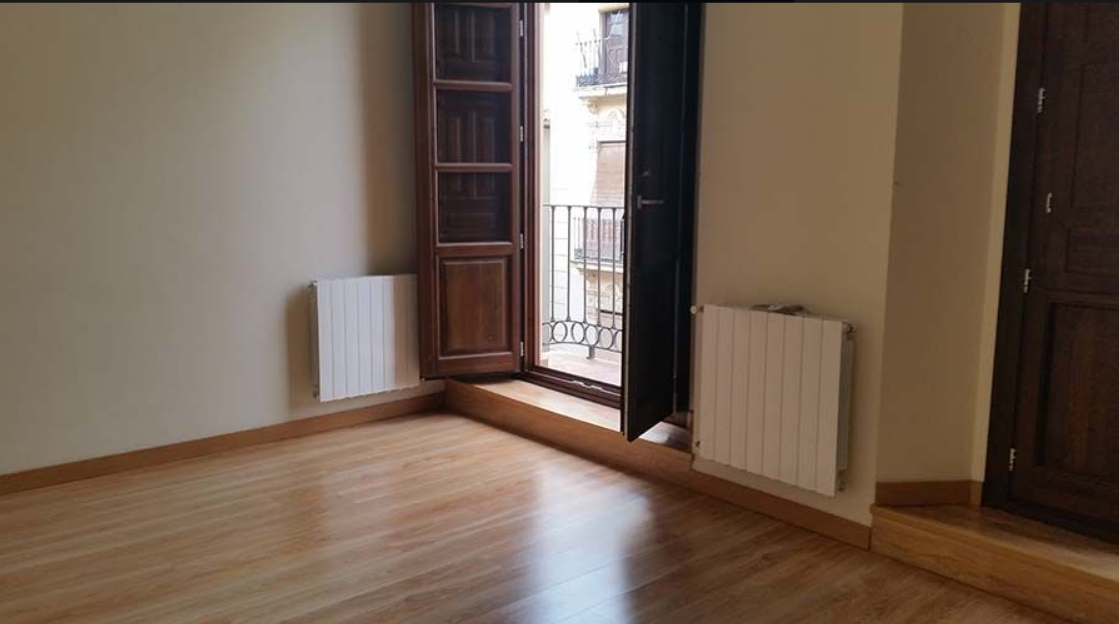 Una habitación vacía con suelo de madera y balcón.