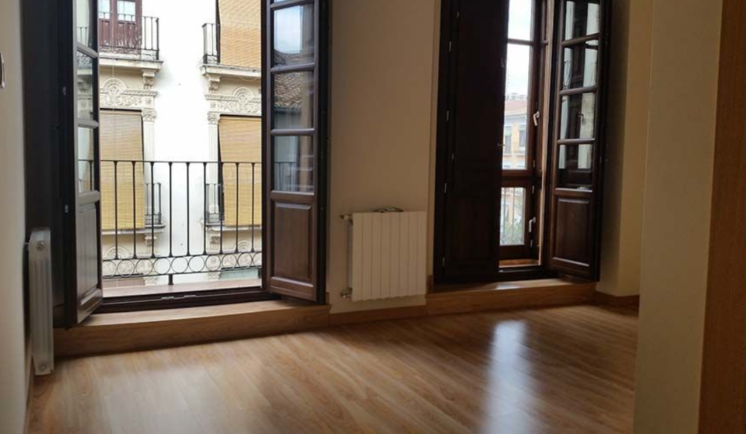 Una habitación vacía con balcón y radiador.