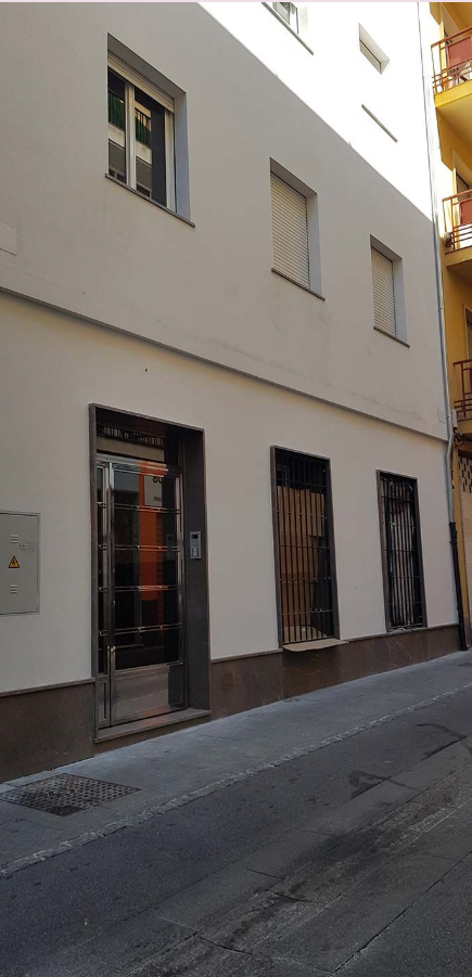 Un edificio con muchas ventanas está al costado de una calle.