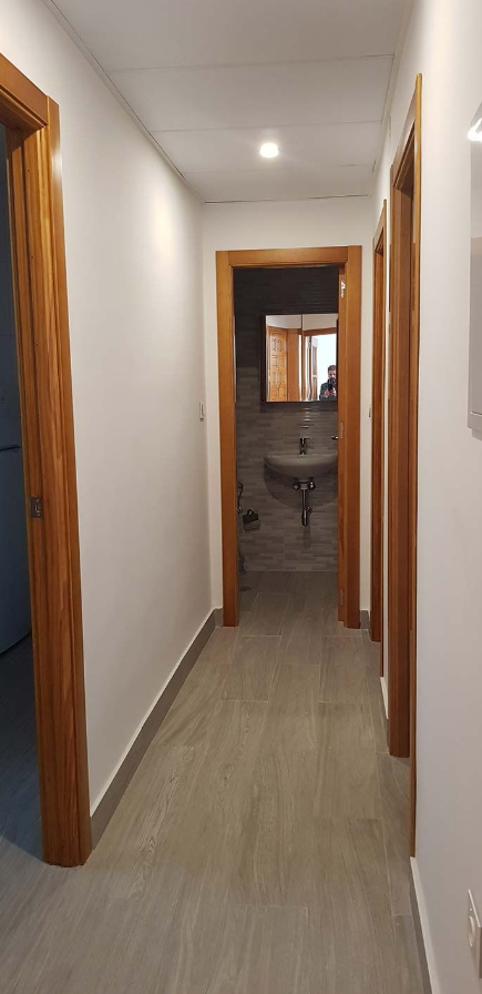 Un largo pasillo que conduce a un baño y un lavabo.