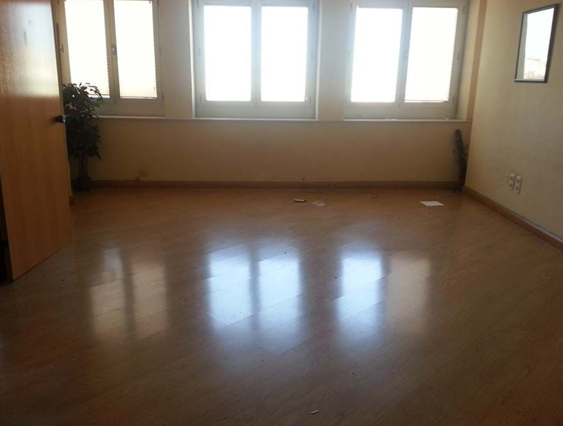 Una habitación vacía con muchas ventanas y suelo de madera.