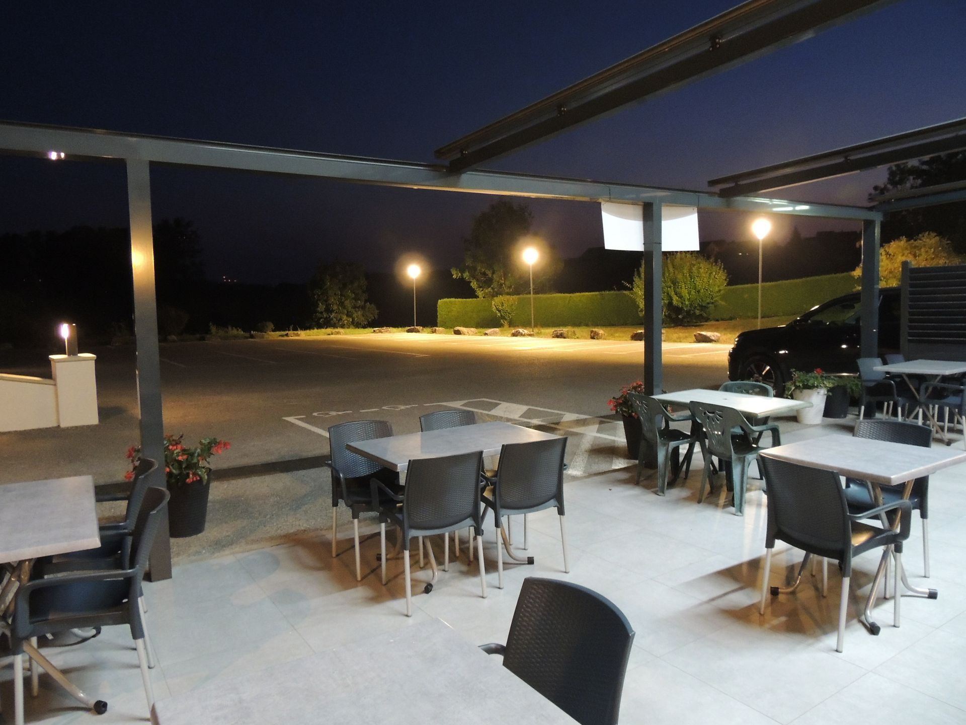 Espace extérieur le soir, tables et chaises sous une pergola