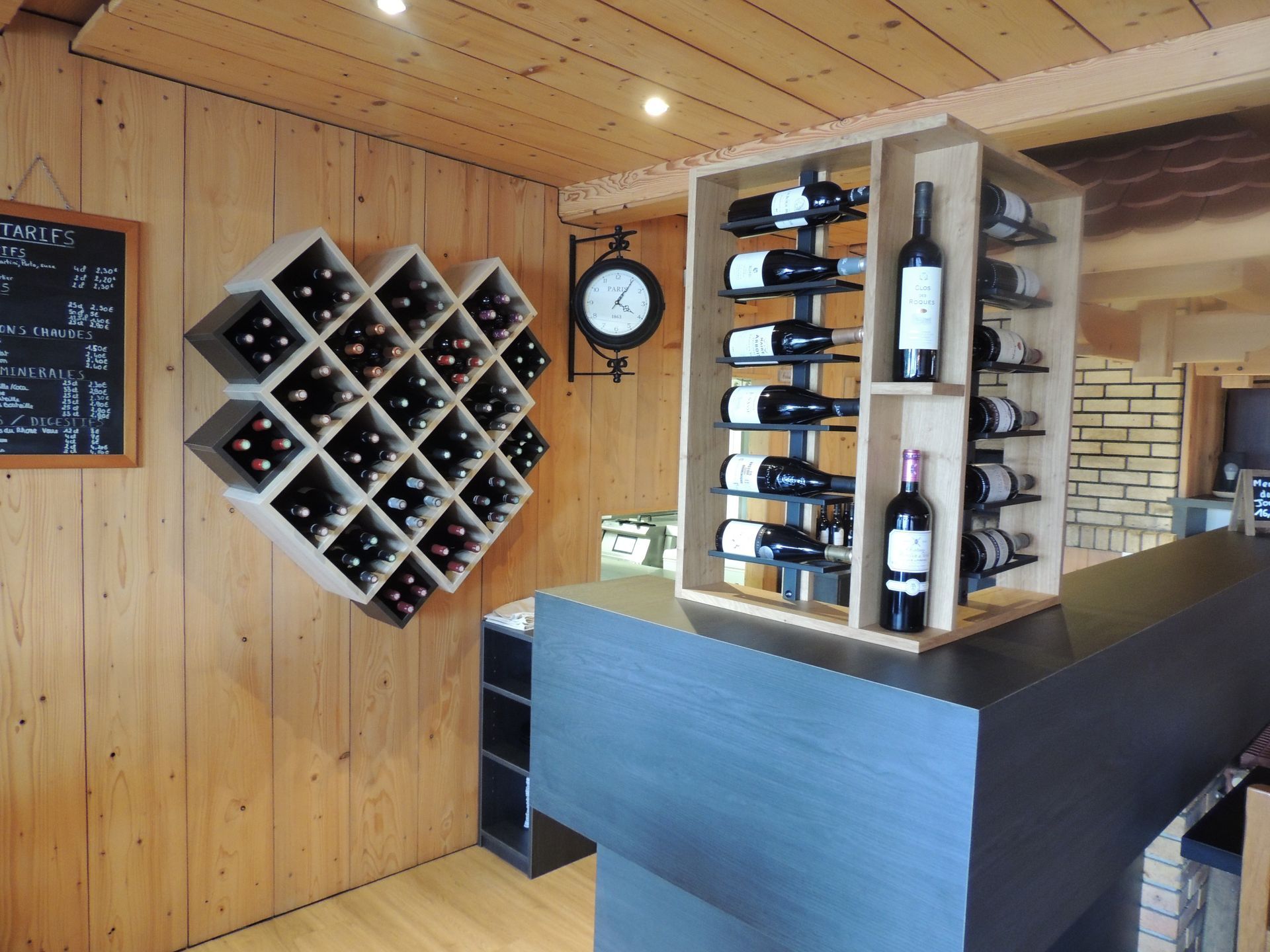 Des casiers à vin en bois au mur et des bouteilles.