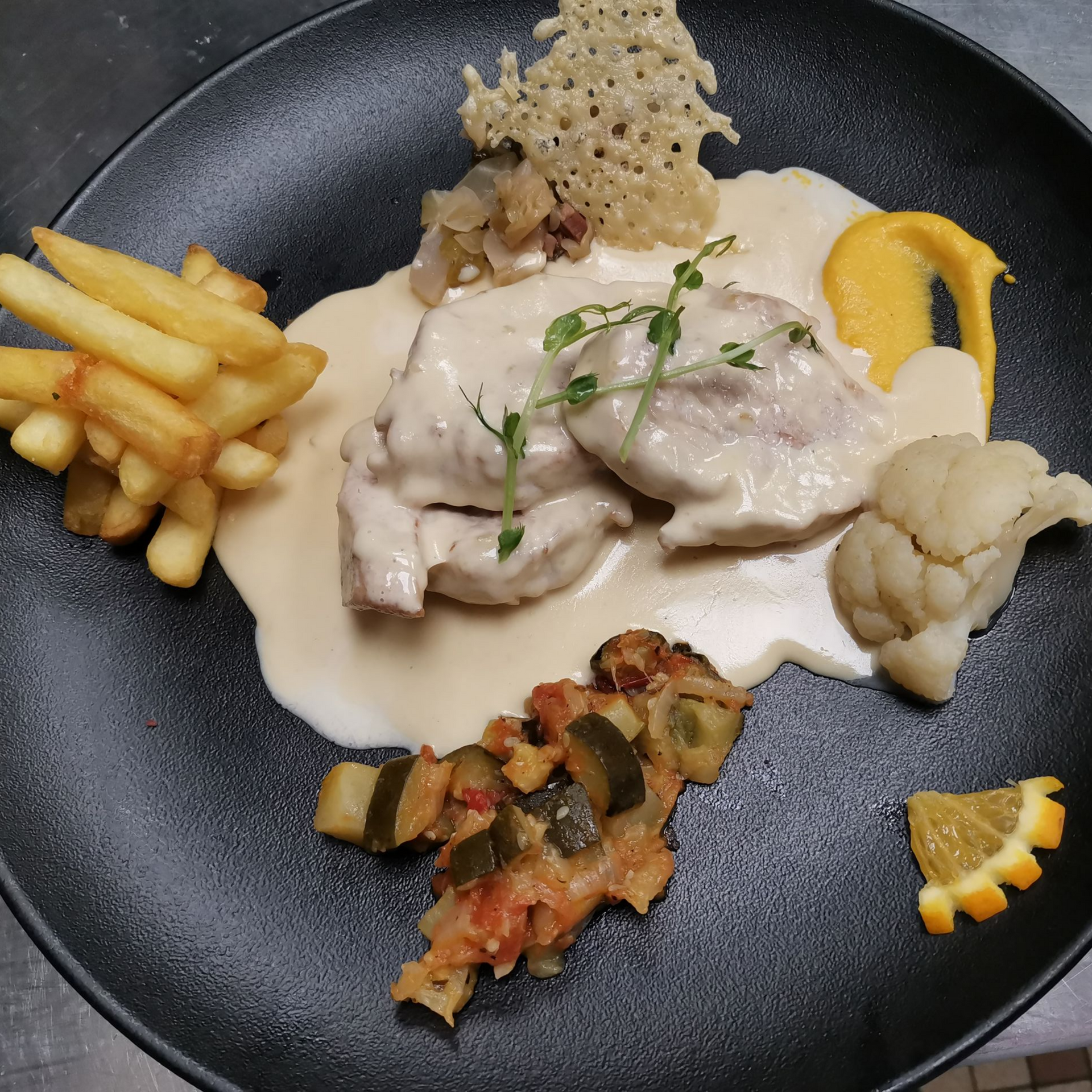 Assiette de poulet à la sauce crémeuse, frites, légumes