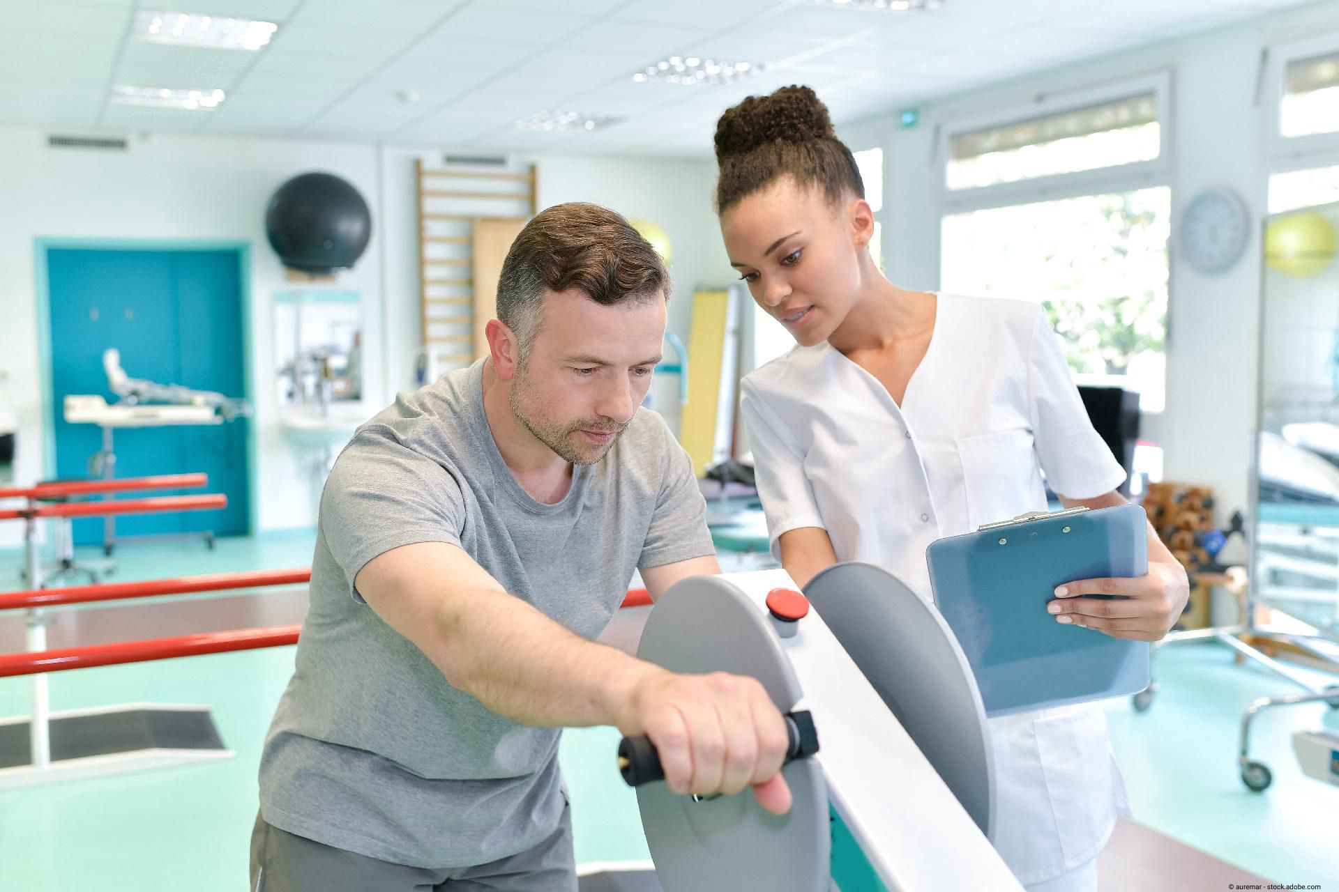 Physiotherapeut betreut Patienten beim Training an einem Rehabilitationsgerät in einer Praxis.