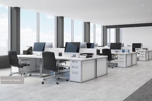 Espace de travail avec des bureaux et ordinateurs et des spots encastrés au plafond avec une lumière naturelle.