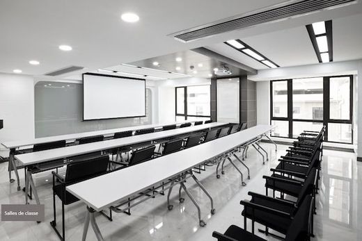 Intérieur de salle de classe avec des tables et des chaises et des spots larges encastrés au plafond.
