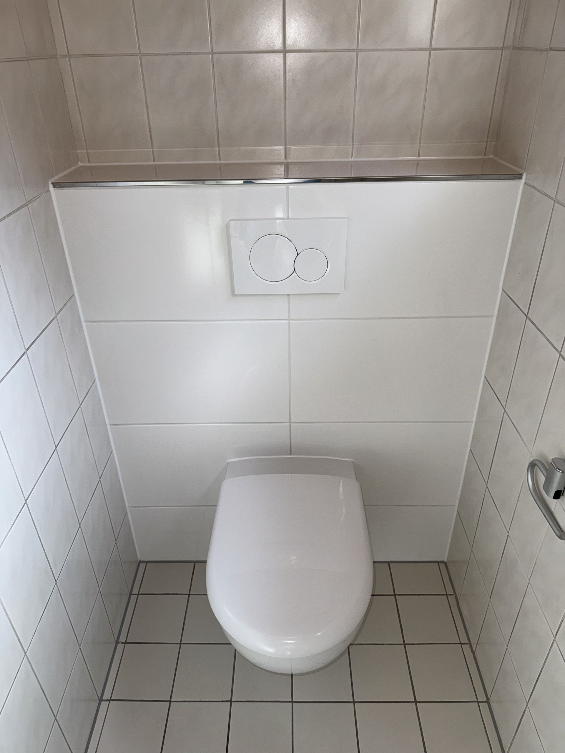 Teilsanierung eines Gäste-WC, nachher mit großen weißen Fliesen und neuer Toilette