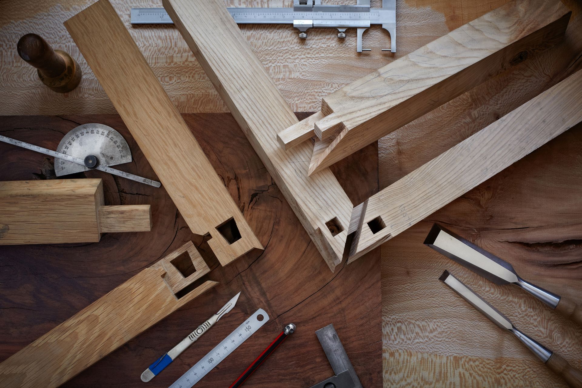 Vers la page Menuiserie Outils de menuiserie et pièces de bois disposés sur un établi, comprenant une scie, une règle et des serre-joints.