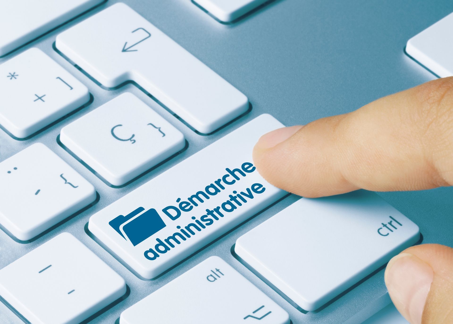 Doigt appuyant sur la touche du clavier étiquetée Démarche administrative sur un clavier d’ordinateur portable blanc.