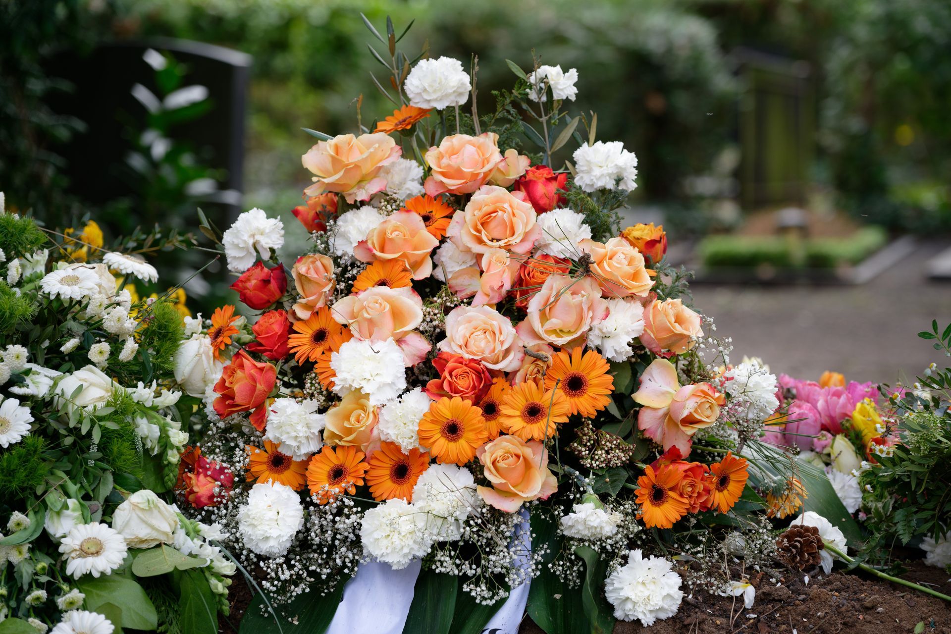 Couronne de fleurs aux tons pêche, orange et blanc sur une tombe