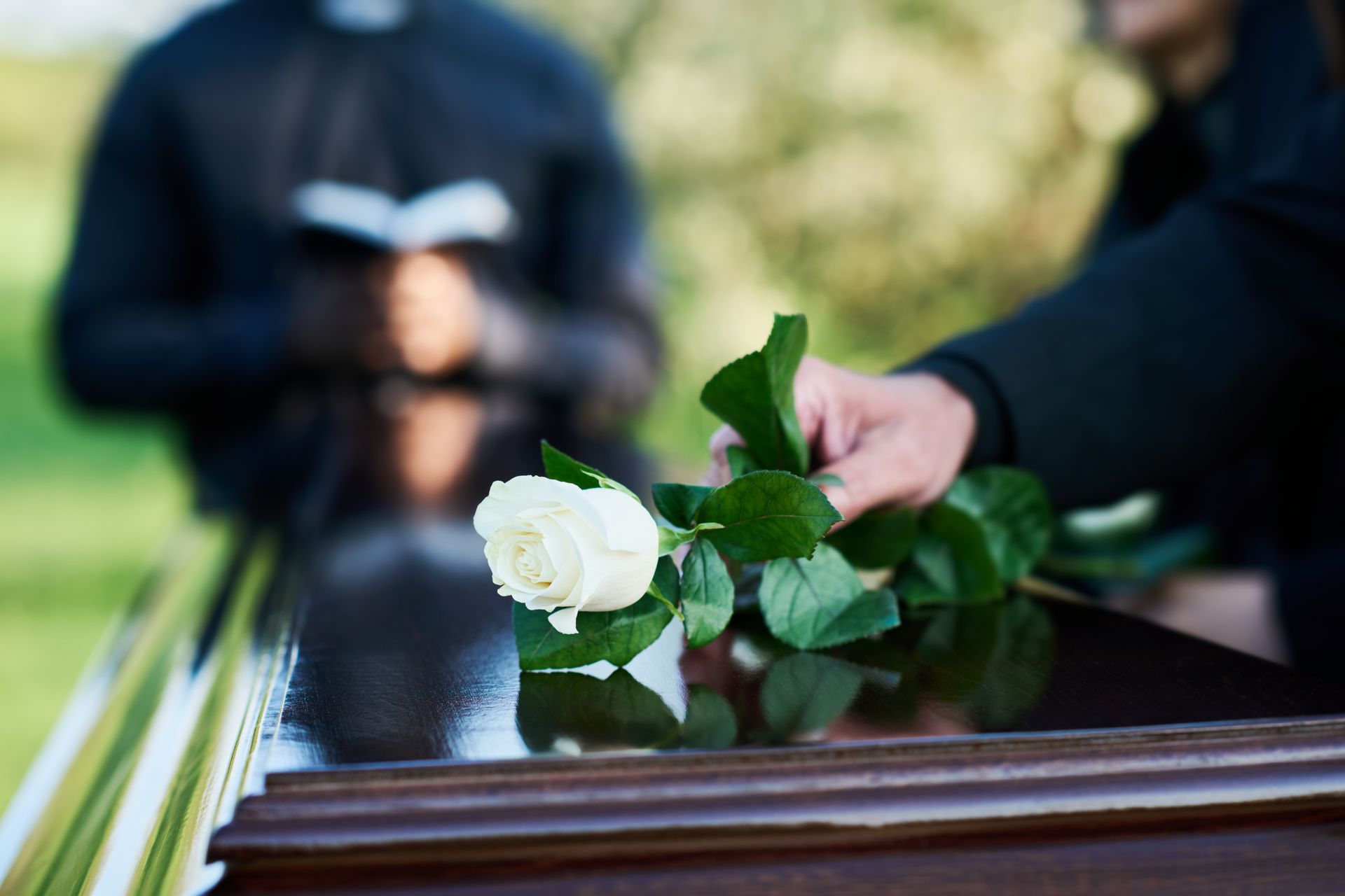Une rose blanche déposée sur un cercueil poli lors d'une cérémonie funéraire