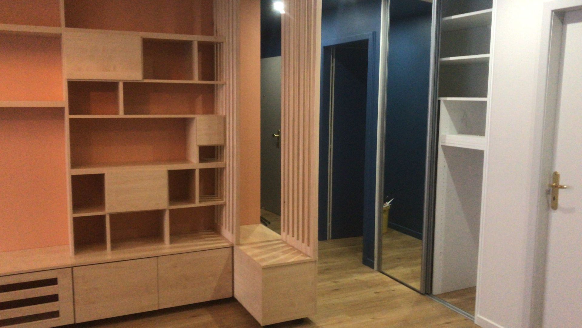 Pièce vide avec étagères en bois intégrées, un miroir et des portes de placard ouvertes