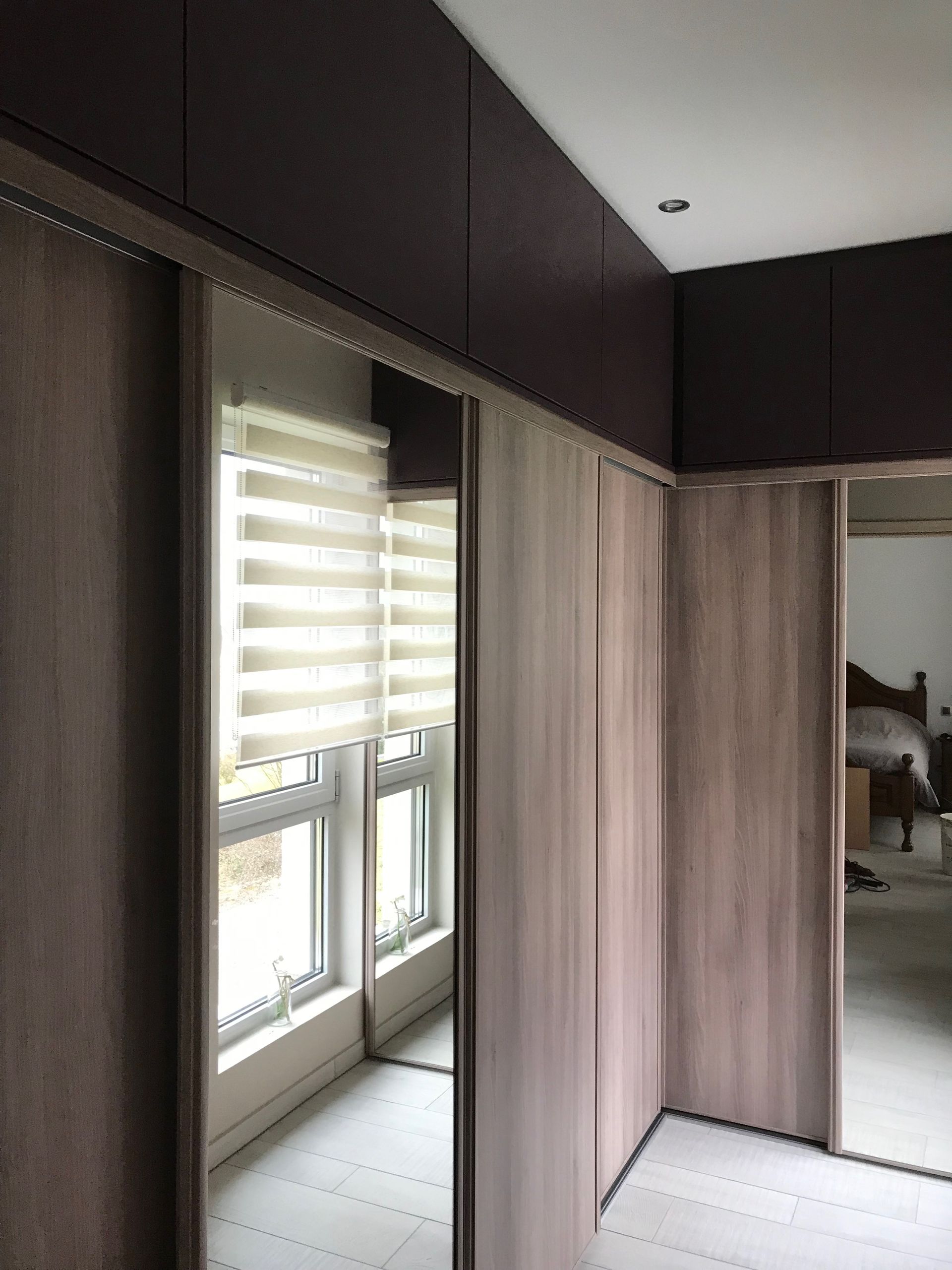 Chambre moderne avec stores, armoire encastrée et porte de placard à miroir