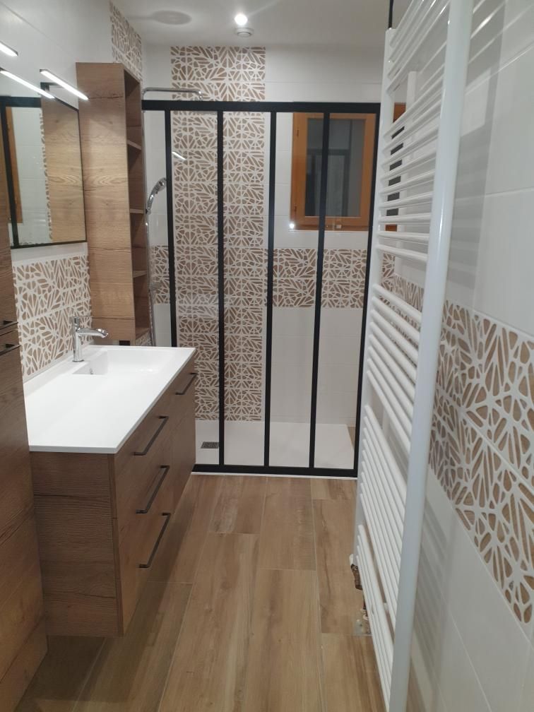 Salle de bains moderne avec meuble-lavabo en bois, douche à l'italienne à cadre noir, carrelage mural à motifs et sèche-serviettes blanc.