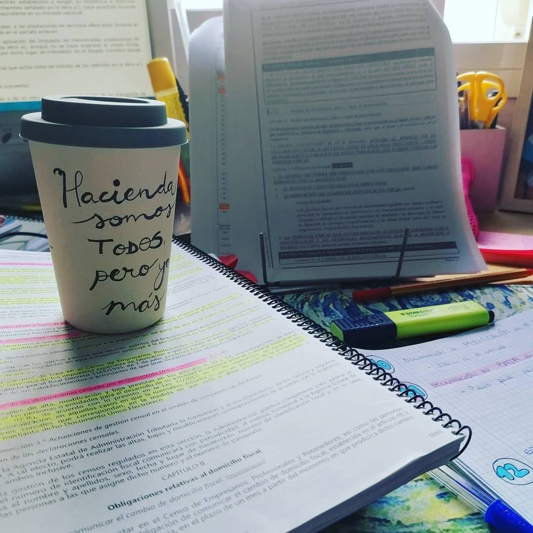 Taza de café sobre un escritorio con notas y marcadores;