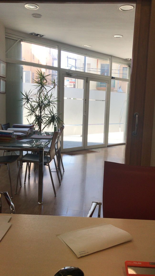 Dos personas están sentadas en una mesa con una balanza de la justicia en el fondo.