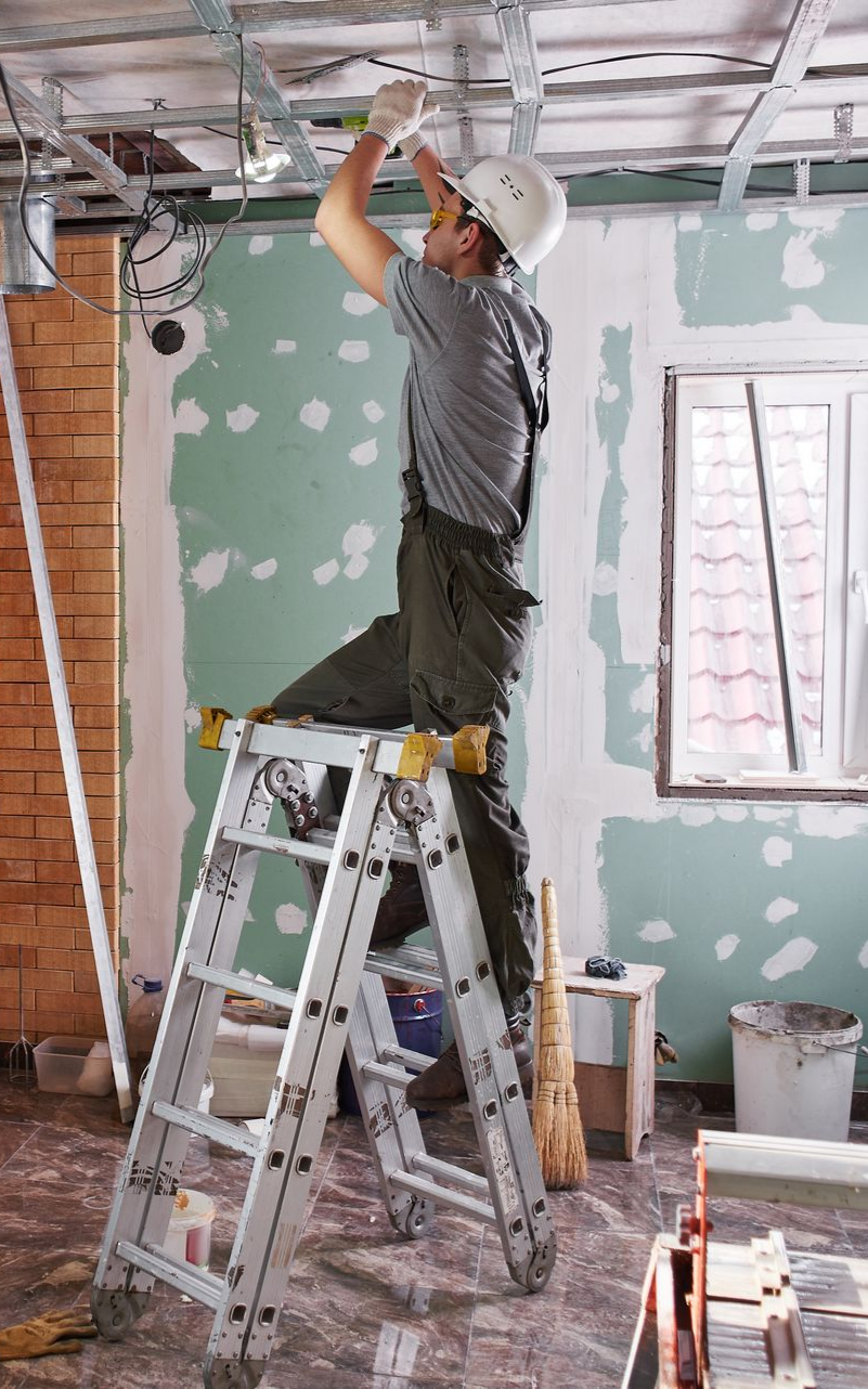 Ouvrier du bâtiment installant des câbles sur une échelle.