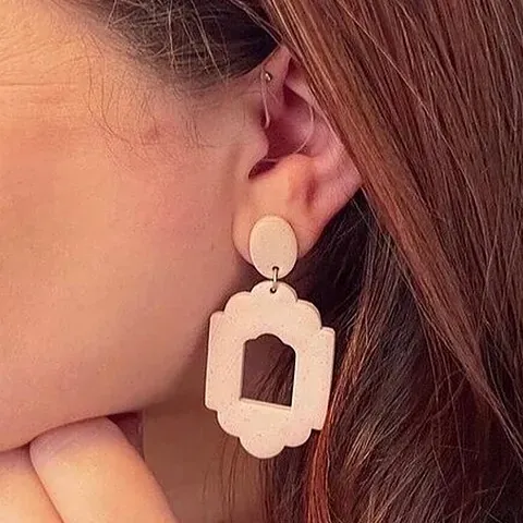 Un primer plano de una mujer que lleva un par de pendientes.