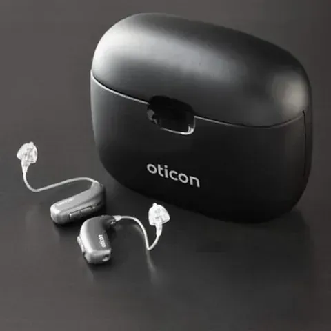 Un par de audífonos junto a un estuche que dice Oticon.
