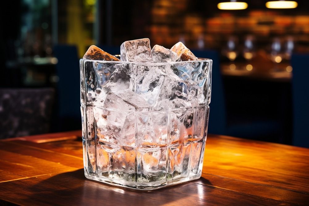 Un vaso lleno de cubitos de hielo está sobre una mesa de madera.
