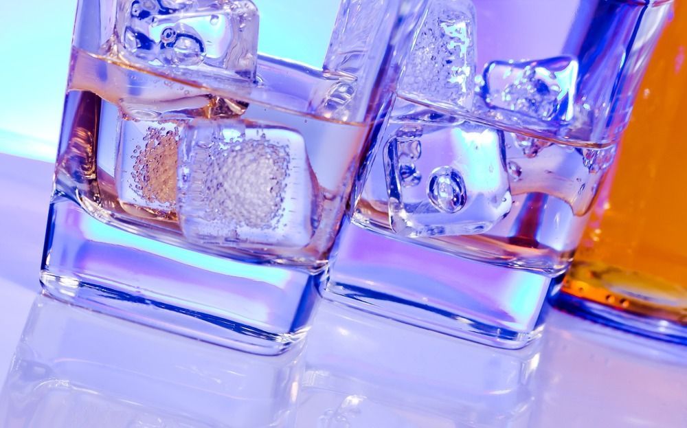 Dos vasos de whisky con cubitos de hielo en una mesa.