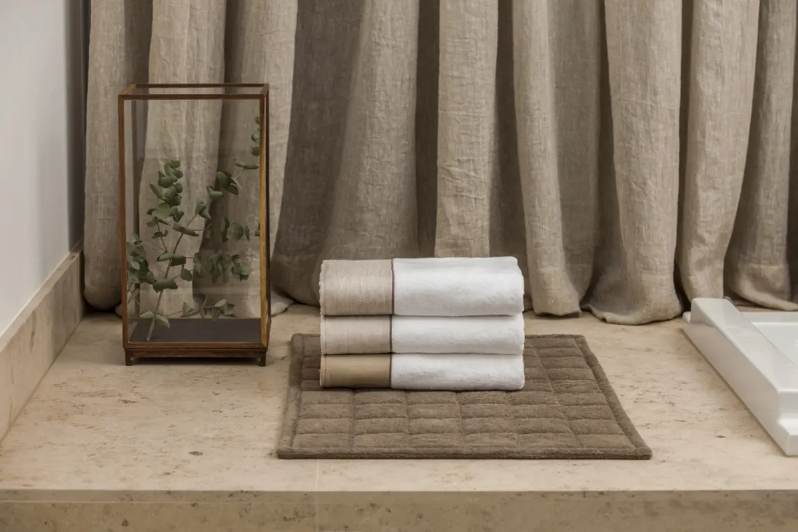 Ein Stapel Handtücher liegt auf einer Badematte auf einer Ablage.