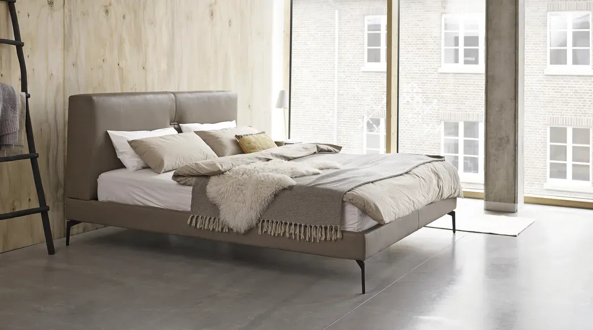 In einem Schlafzimmer steht ein Bett neben einem Fenster.