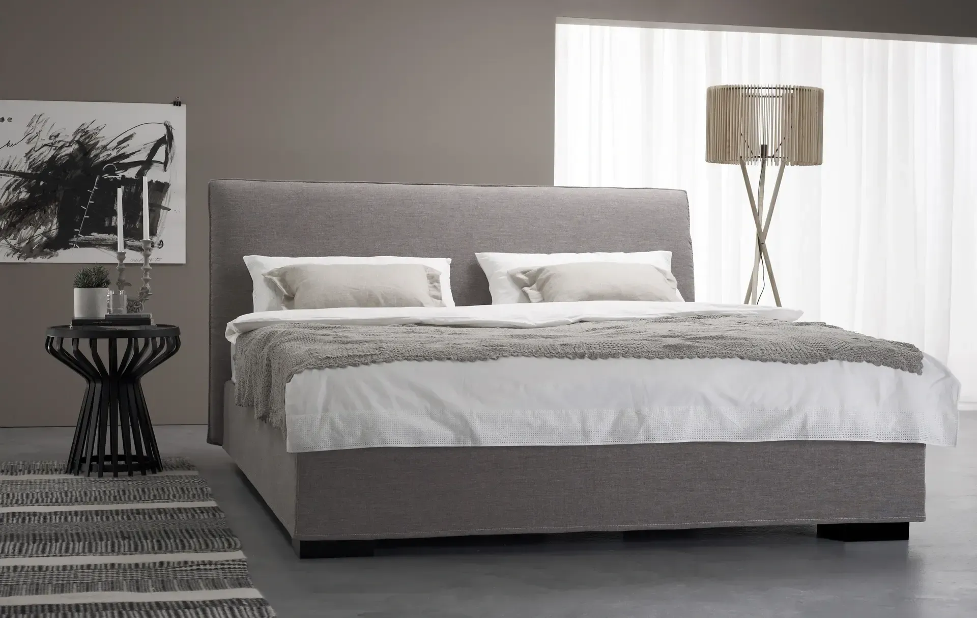 Ein Schlafzimmer mit Bett, Nachttisch, Lampe und Gemälde an der Wand.