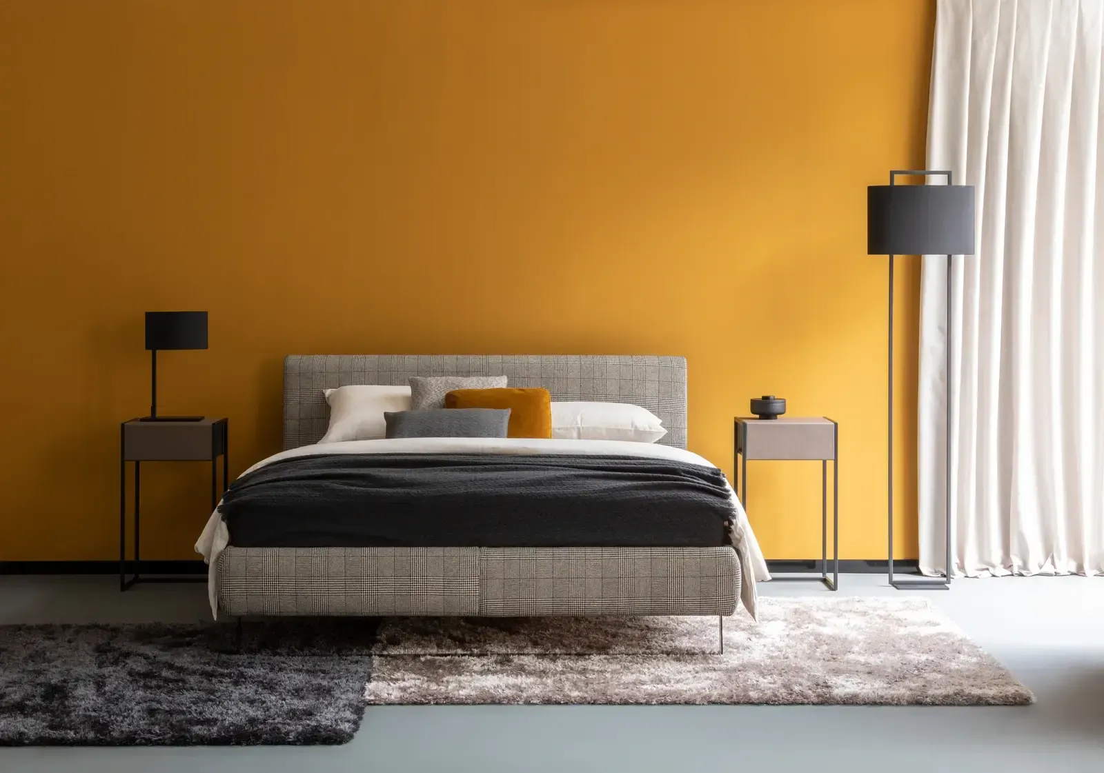 Ein Schlafzimmer mit gelben Wänden, einem Bett, Nachttischen und einem Teppich.