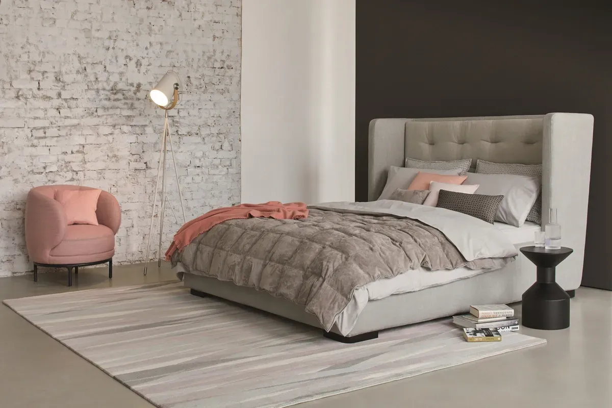 Ein Schlafzimmer mit Bett, Stuhl, Lampe und Teppich.