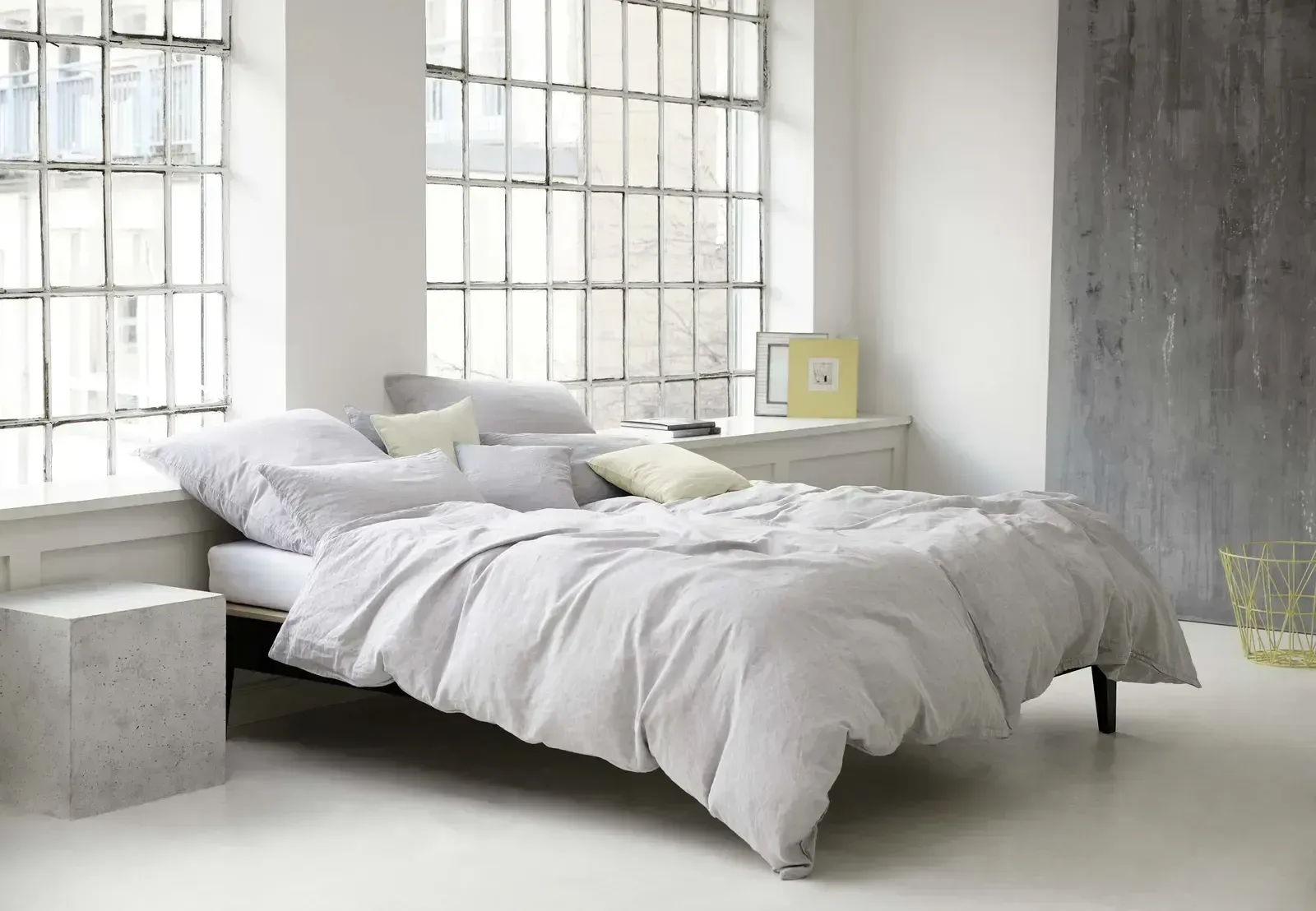 Ein Bett mit weißen Laken und Kissen in einem Zimmer mit einem Fenster.