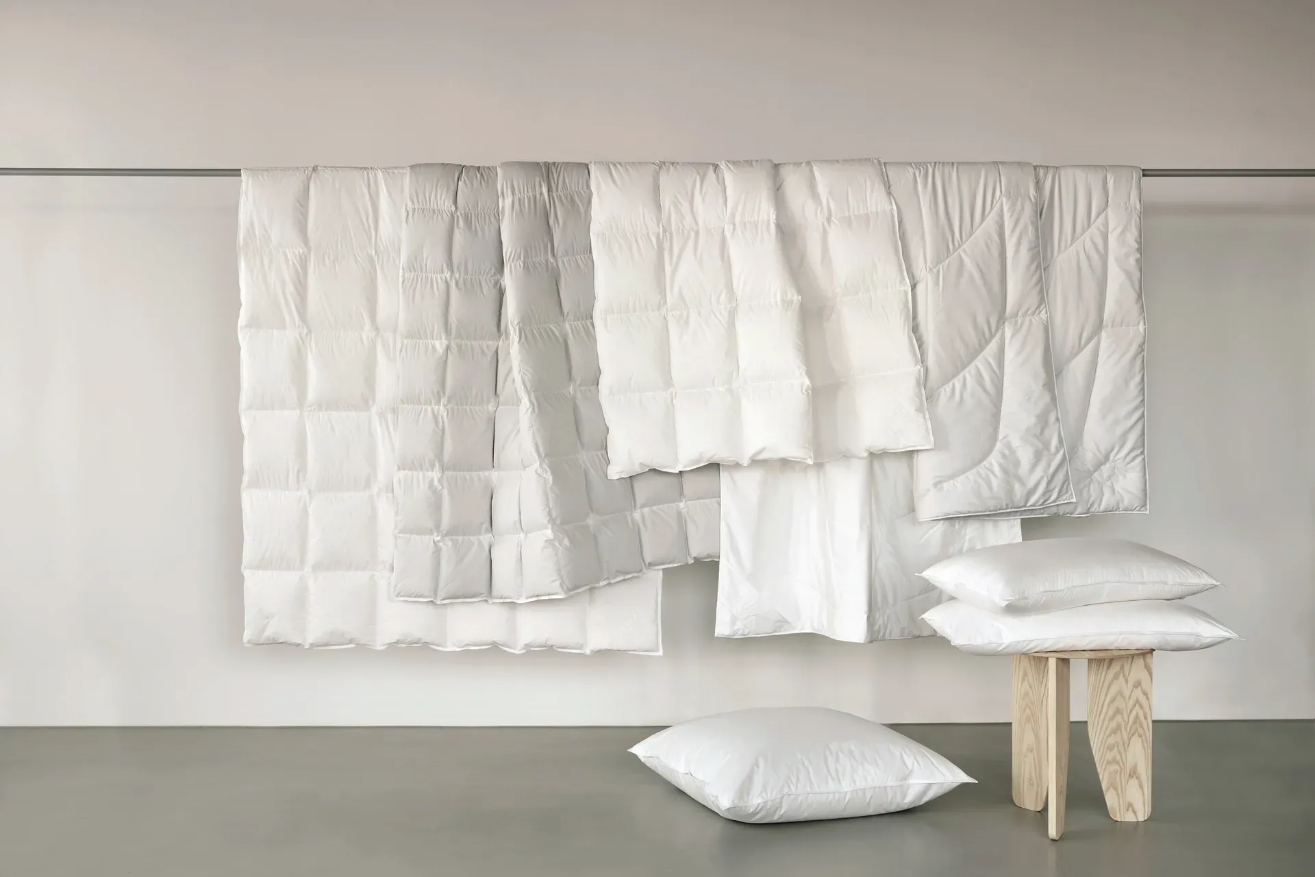 An der Wand hängen viele weiße Decken und Kissen.